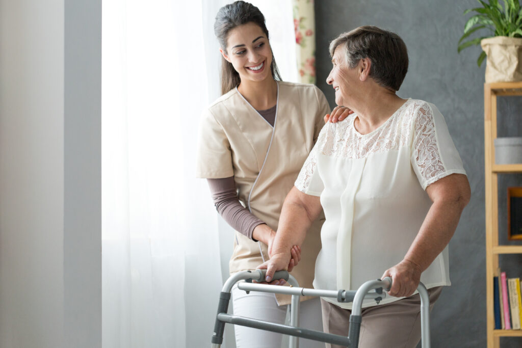 This image is of a carer walking supporting an older person to walk with their walking frame.